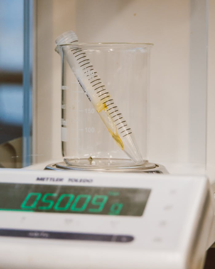 Close-up of lab equipment featuring a beaker, sample tube, and digital scale for precise weighing.